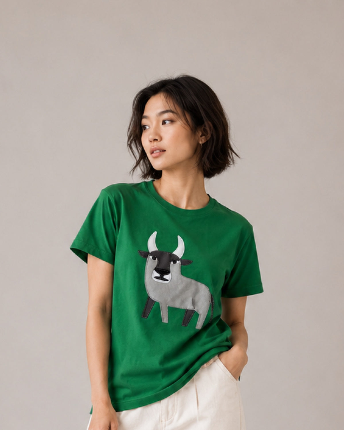 Kvinde i HILP's grønne t-shirt med stjernetegnet Tyren, den grå tyr skåret ud af stof og syet på bomuldsjerseyen