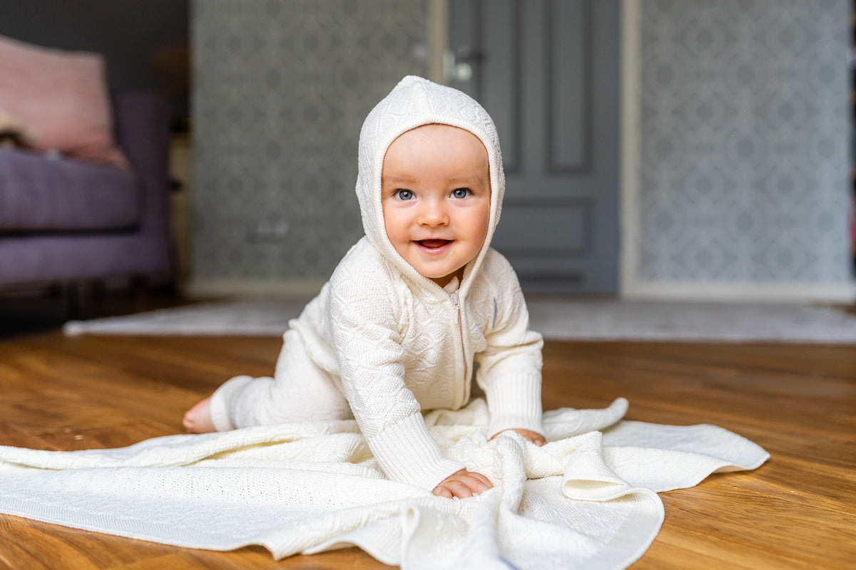 Baby in a knitted merino romper on the HAPPINESS merino blanket by Wool In Love, made from OEKO-TEX certified yarn