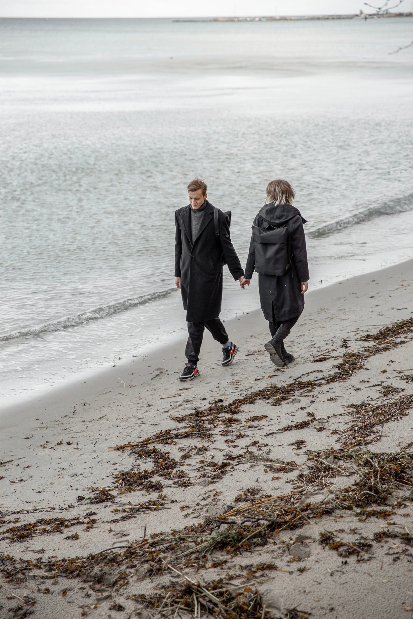 Sale at Snøluv: couple on a Baltic beach with the Nordhale Hølar weatherproof backpack