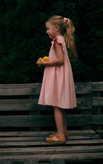Kids muslin dress Sisi in peach, worn outdoors