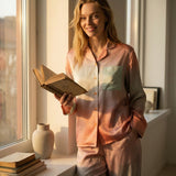 Tæwas Sunset silk pyjama set worn while reading a book by the window