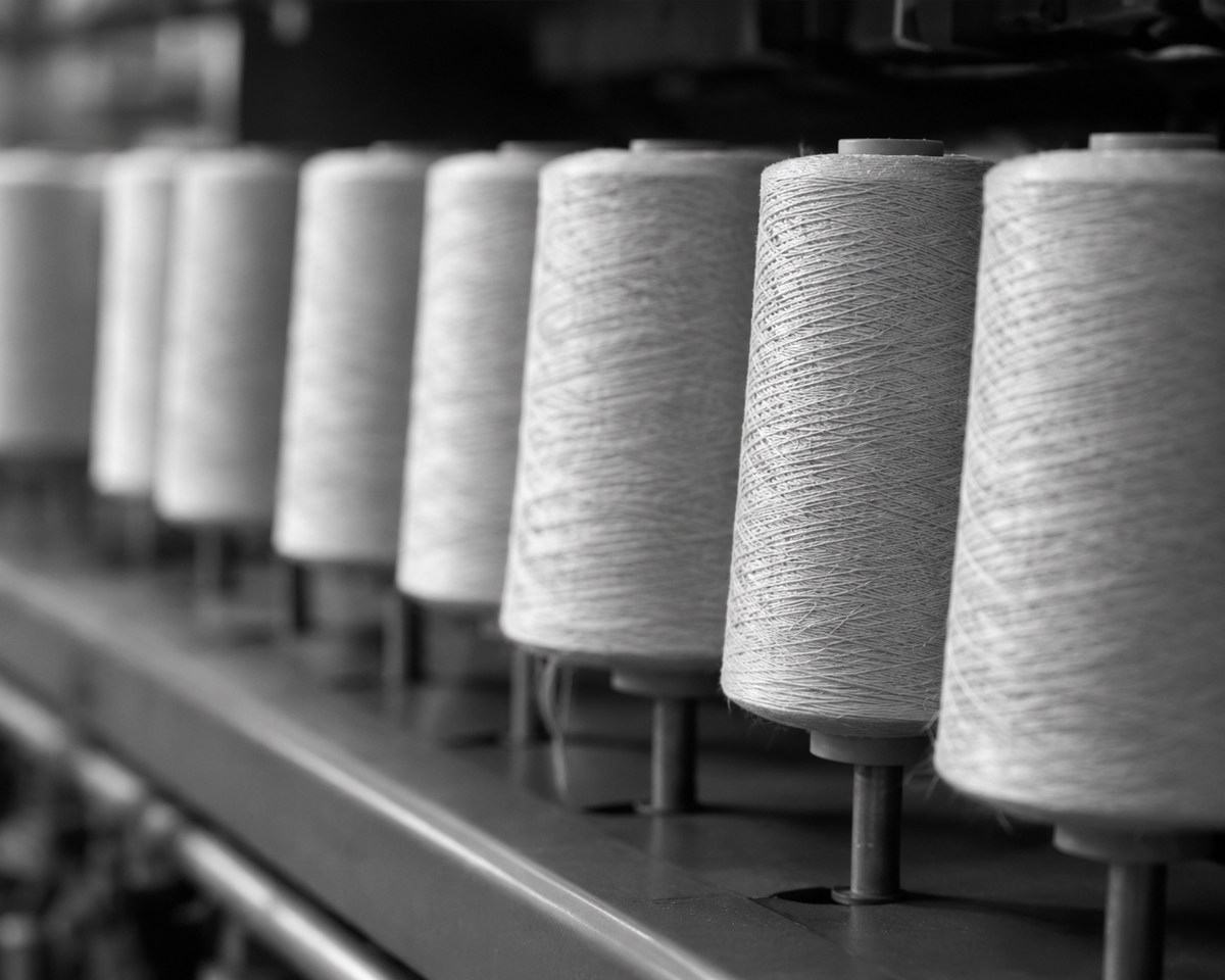 Rows of natural yarn cones on a spinning machine, in black and white